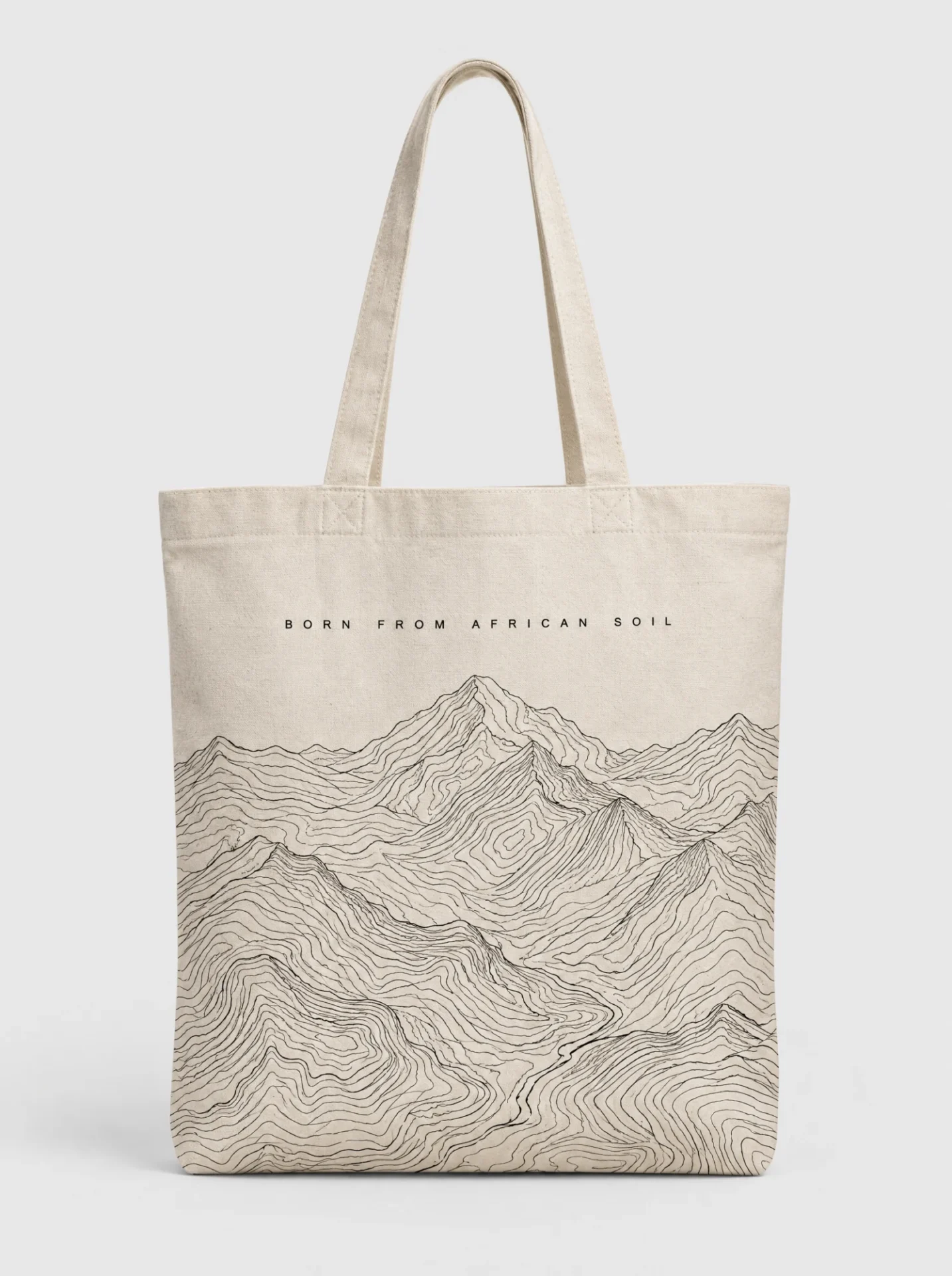 Natural canvas tote bag printed with black contour-line mountains and the words BORN FROM AFRICAN SOIL